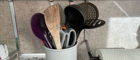 A kitchen with a utensil holder containing a wooden spoon, a purple spatula, and a black spatula.