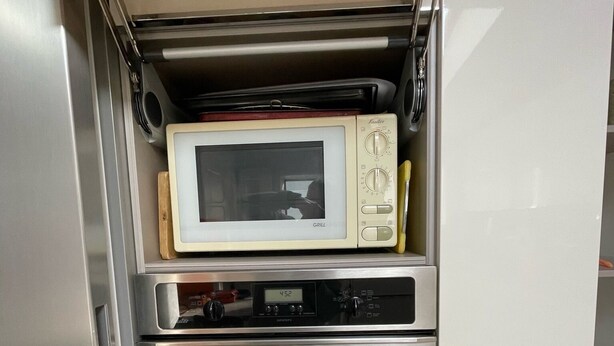 A kitchen with a built-in microwave, oven, and a small refrigerator.