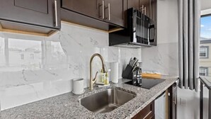 A kitchen with dark wooden cabinets, a stainless steel sink, and a black microwave. - Brand New Modern Home /w Rooftop Downtown Skyview (Philadelphia)
