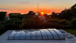 Eine Solaranlage auf einem Dach mit Blick auf einen Sonnenuntergang über einem Wohngebiet.