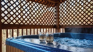Un bain à remous avec deux verres posés sur le bord, entouré d’une structure en treillis de bois.