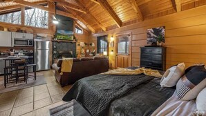 L’intérieur d’un chalet confortable, avec une cuisine, un coin repas et un grand lit.
