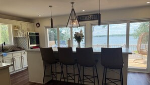 Una cocina con barra, ventanas amplias y vista a un lago.