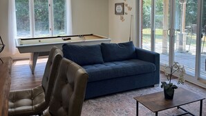 Una sala de estar moderna con mesa de billar, un sofá azul, sillones de cuero y una mesa de centro.
