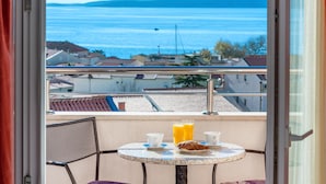 A balcony with a table set for breakfast, overlooking a coastal view. - Awesome apartment in Baska Voda (Baska Voda)