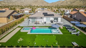 A residential area with a swimming pool, patio furniture, and a mountain backdrop. - Salida Del Sol by Rather Be Properties (Desert Hot Springs)