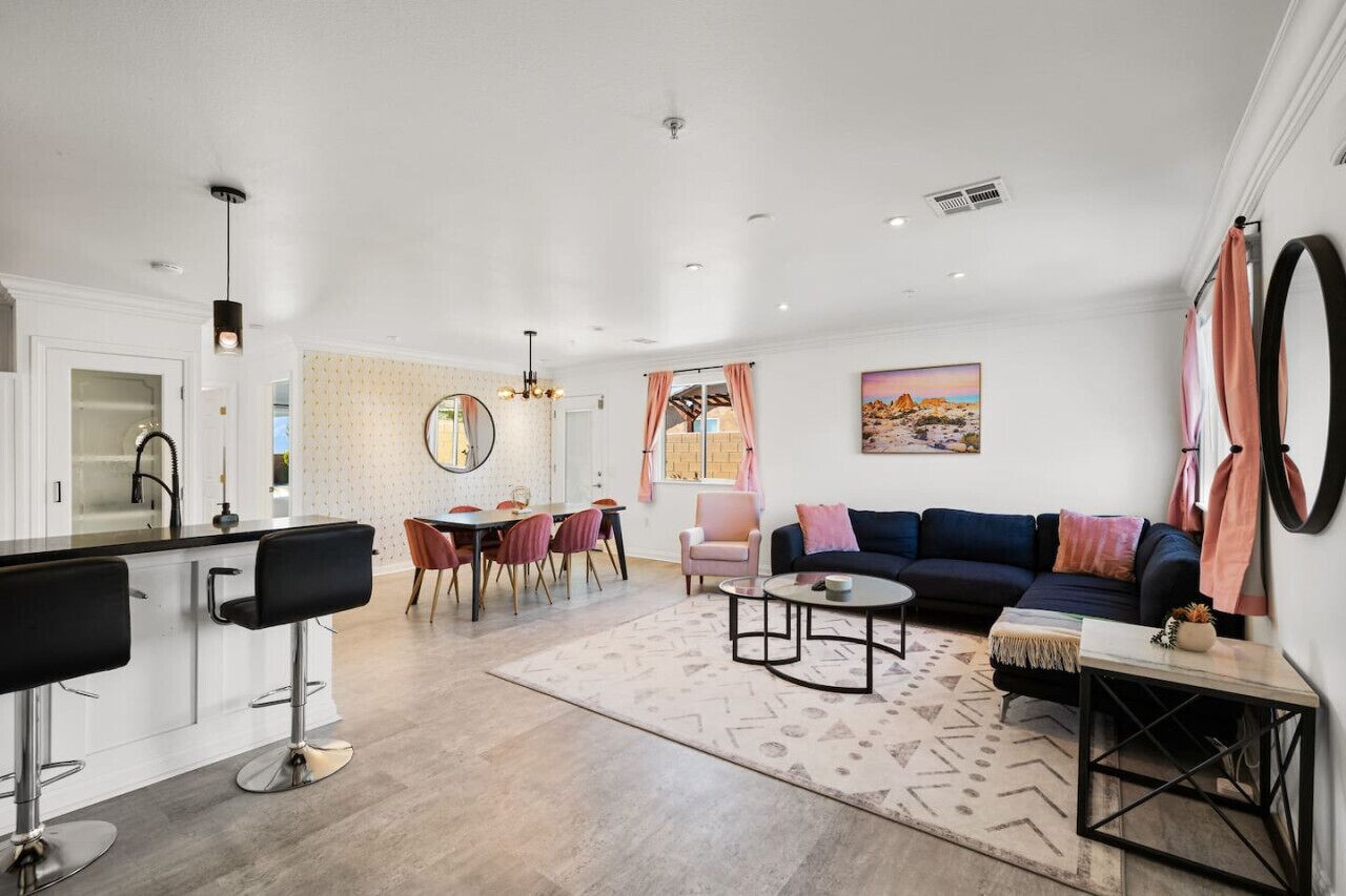Ein modernes Wohnzimmer mit einem dunkelblauen Sofa, einem runden Couchtisch und einer Küchenzeile mit Bar.