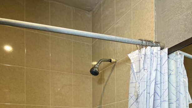 Une douche avec une porte en verre, un pommeau de douche à main et un porte-serviettes.