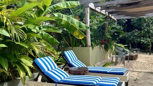 A beachside lounge area with two striped lounge chairs and a small round table.