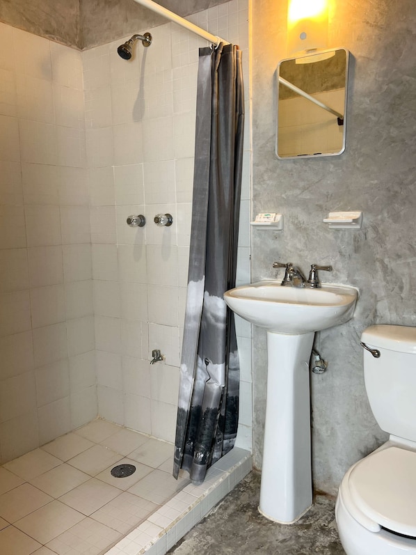 Un baño con ducha, lavamanos e inodoro.