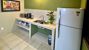 Una cocina compacta con un lavamanos, una cafetera, un tostador y un refrigerador.