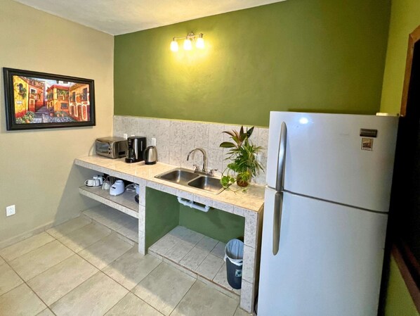 A compact kitchen with a sink, a coffee maker, a toaster, and a refrigerator.