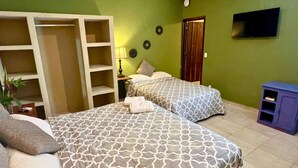 Un dormitorio con dos camas, un armario, un televisor y una mesita.