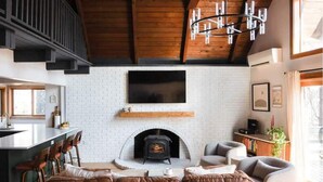 Uma sala de estar aconchegante com lareira, um sofá e uma televisão na parede.