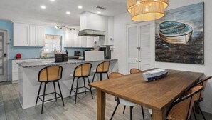 A modern kitchen with white cabinets, a wooden dining table, and wicker chairs. - ParadiZe on Lake LBJ Open water 6 Bed 5 Bth Boat slip 2 jet ski ramps (Kingsland)