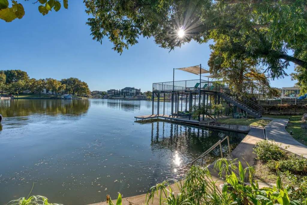 A tranquil lakeside setting with a dock, a covered seating area, and a clear view of the surrounding landscape.