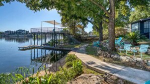 A lakeside deck with a small dock, outdoor seating, and a stone pathway. - ParadiZe on Lake LBJ Open water 6 Bed 5 Bth Boat slip 2 jet ski ramps (Kingsland)