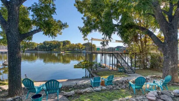 A lakeside deck with chairs and a small table, surrounded by trees and a dock extending into the water. - ParadiZe on Lake LBJ Open water 6 Bed 5 Bth Boat slip 2 jet ski ramps (Kingsland)