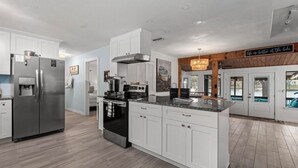 A modern kitchen with white cabinetry, stainless steel appliances, and a large island. - ParadiZe on Lake LBJ Open water 6 Bed 5 Bth Boat slip 2 jet ski ramps (Kingsland)