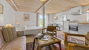 Et moderne, godt oplyst værelse med seng, sofa, spisebord og et tekøkken.