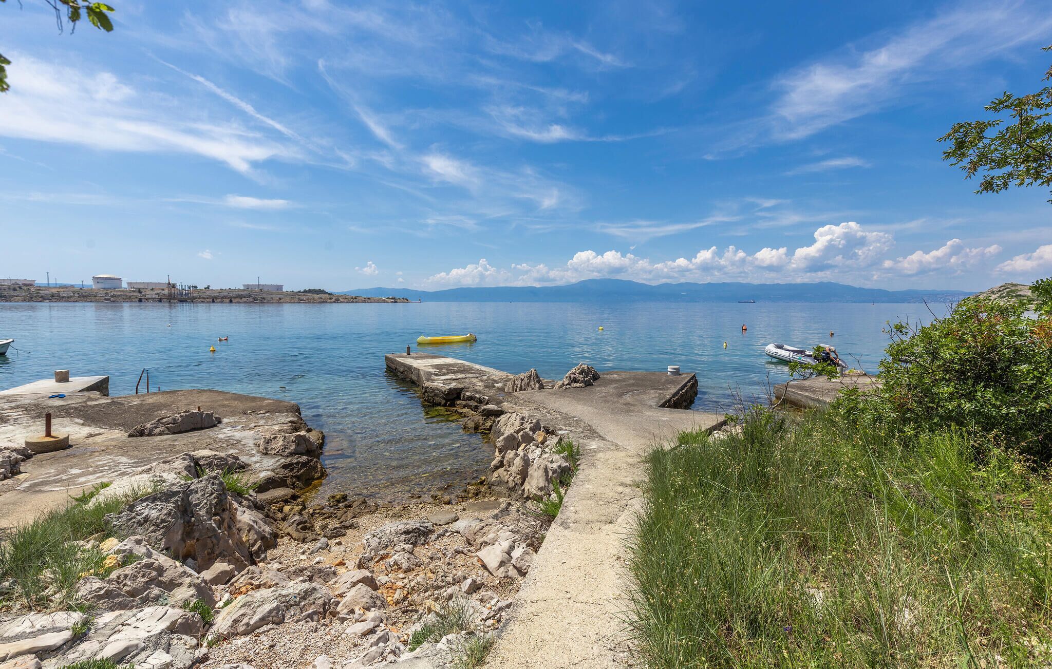 A coastal scene with a clear sky, rocky shoreline, and calm water.