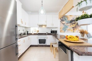 Una cocina moderna con gabinetes blancos, electrodomésticos de acero inoxidable y encimera de madera.
