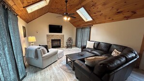 A cozy living room with a fireplace, a sofa, a coffee table, and a ceiling fan. - The Winterbrook Mountain House.
Bike Week Garage Owls Nest Golf (Campton)