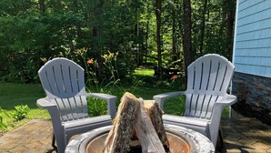 A fire pit with two Adirondack chairs in a garden setting. - The Winterbrook Mountain House.
Bike Week Garage Owls Nest Golf (Campton)