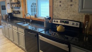 A kitchen with a black countertop, stainless steel appliances, a window with blinds, and a brick backsplash. - The Winterbrook Mountain House.
Bike Week Garage Owls Nest Golf (Campton)