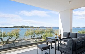 Un balcon avec vue sur un lac, une table avec une bouteille et un canapé.