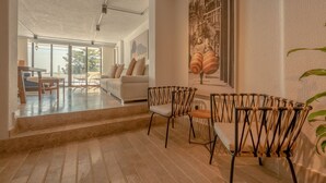 A spacious living area with a white sofa, a dining table with chairs, and a staircase leading to another room. - Casa Griega By Wynwood House (Cartagena)