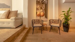 A modern living room with a sofa, two chairs, a staircase, a large framed artwork, and a potted plant. - Casa Griega By Wynwood House (Cartagena)