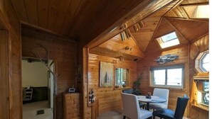 Interno di una baita in legno con zona pranzo, una scala e un lucernario.