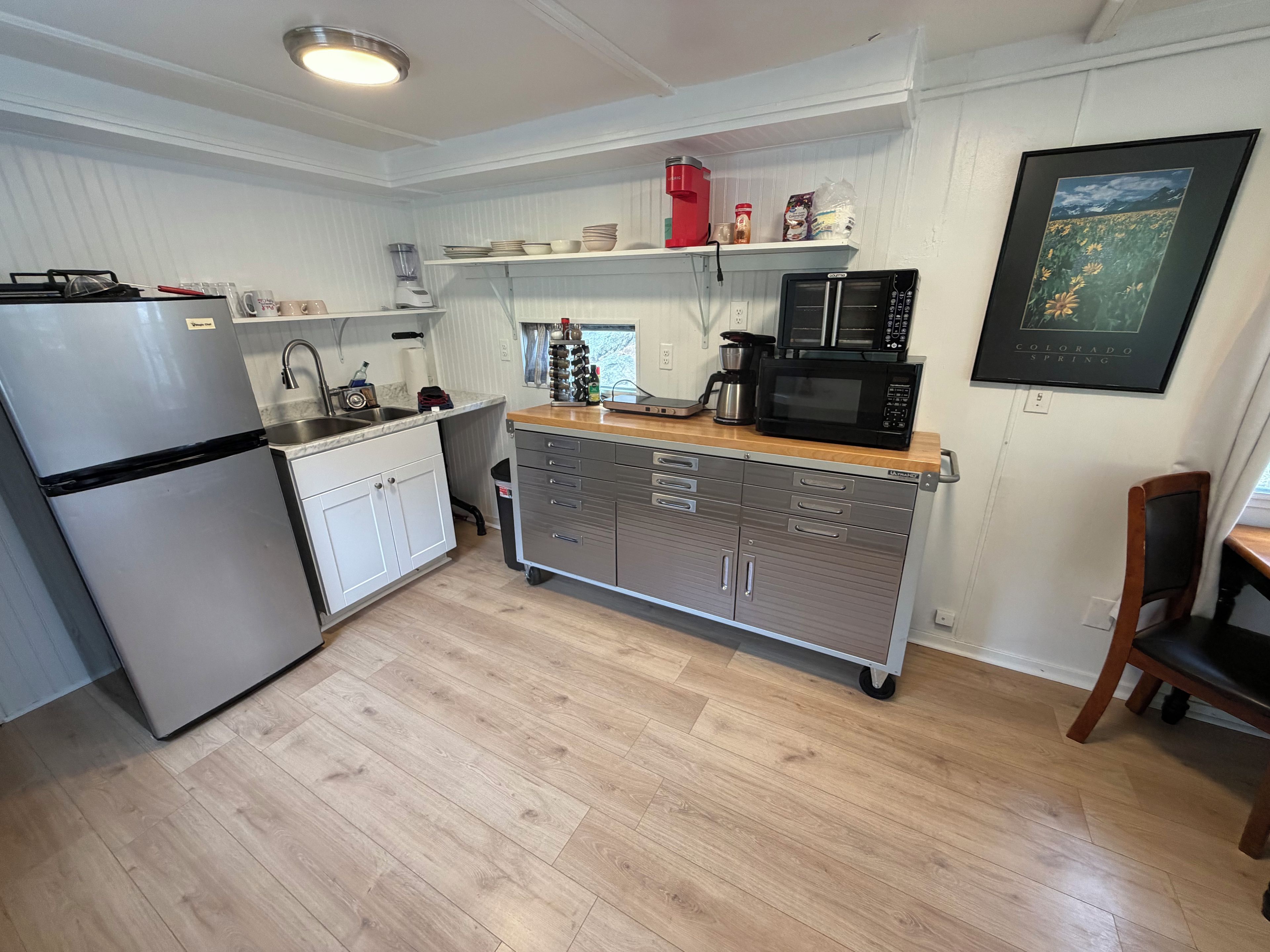 Une cuisine compacte équipée d’un réfrigérateur, d’un four à micro-ondes, d’une machine à café et d’un petit placard.