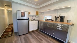 Een kleine keuken met een koelkast, spoelbak en roestvrijstalen kastjes.