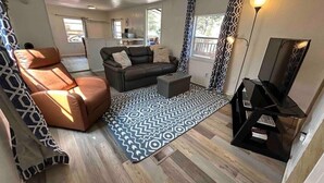 Un espacio habitable compacto con un sofá, una silla, una mesa de centro y un mueble para televisión.