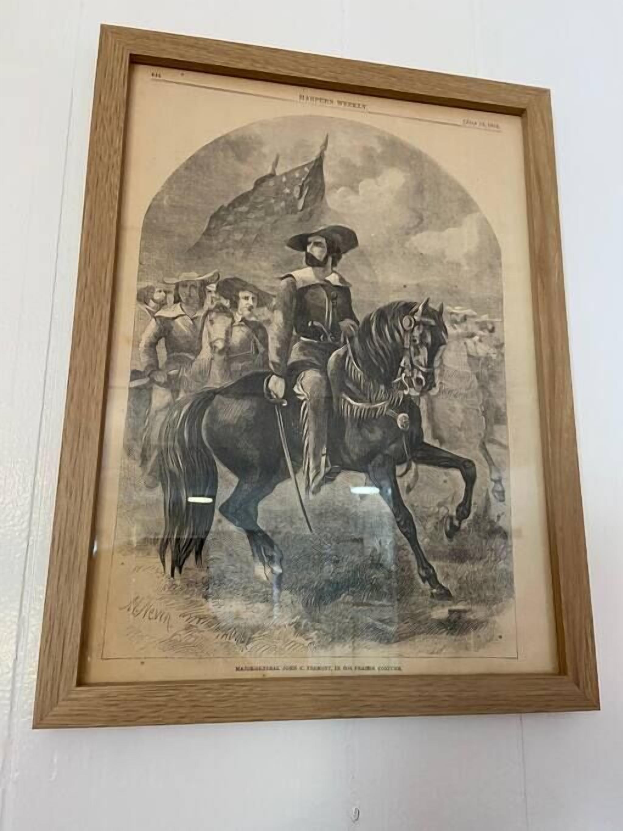 Ilustración histórica enmarco de un hombre a caballo, rodeado de otras figuras, con una bandera al fondo.