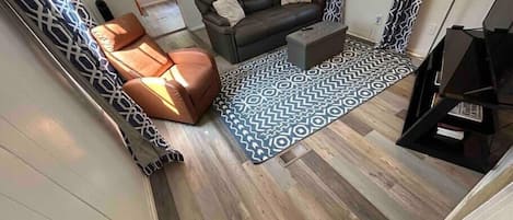 Ein Wohnzimmer mit Sofa, Sessel, Couchtisch und einem gemusterten Teppich.
