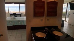 A hotel room with a bed, two sinks, a ceiling fan, and a view of the beach. - AMI Beach + Gulf View Retreat - Dog-friendly (Bradenton Beach)