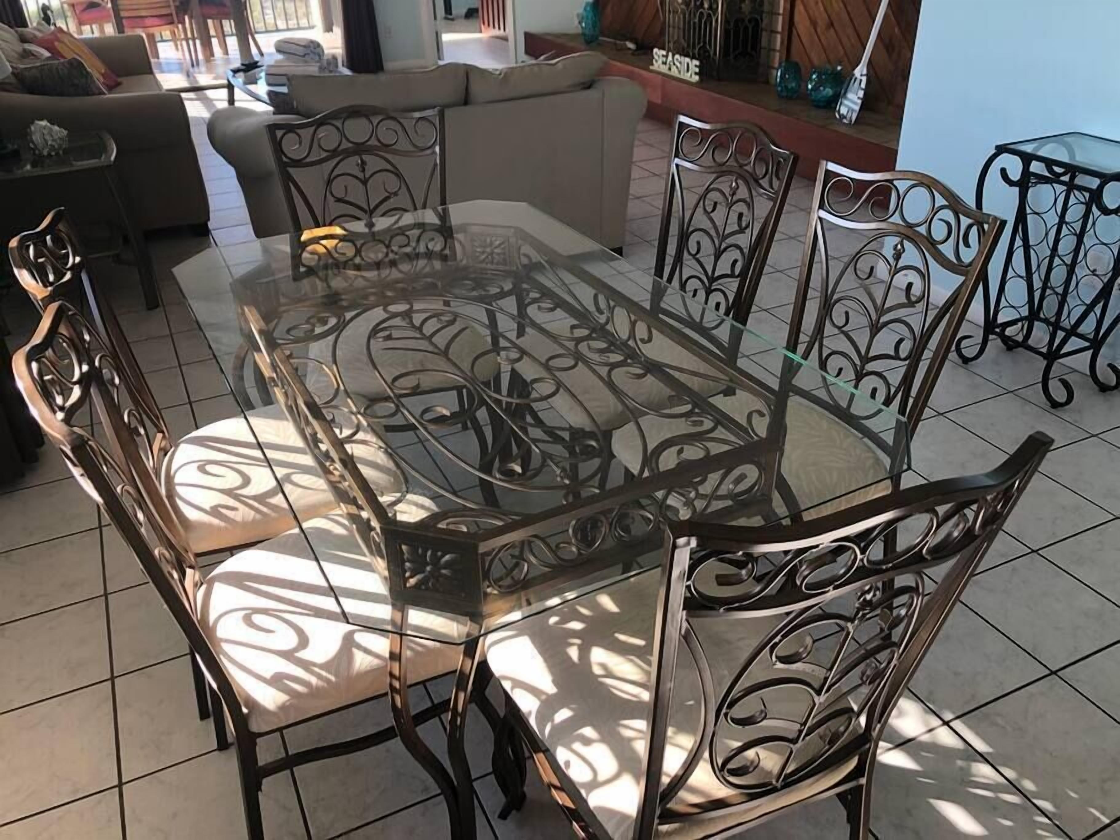 A dining area with a glass-top table surrounded by ornate metal chairs.