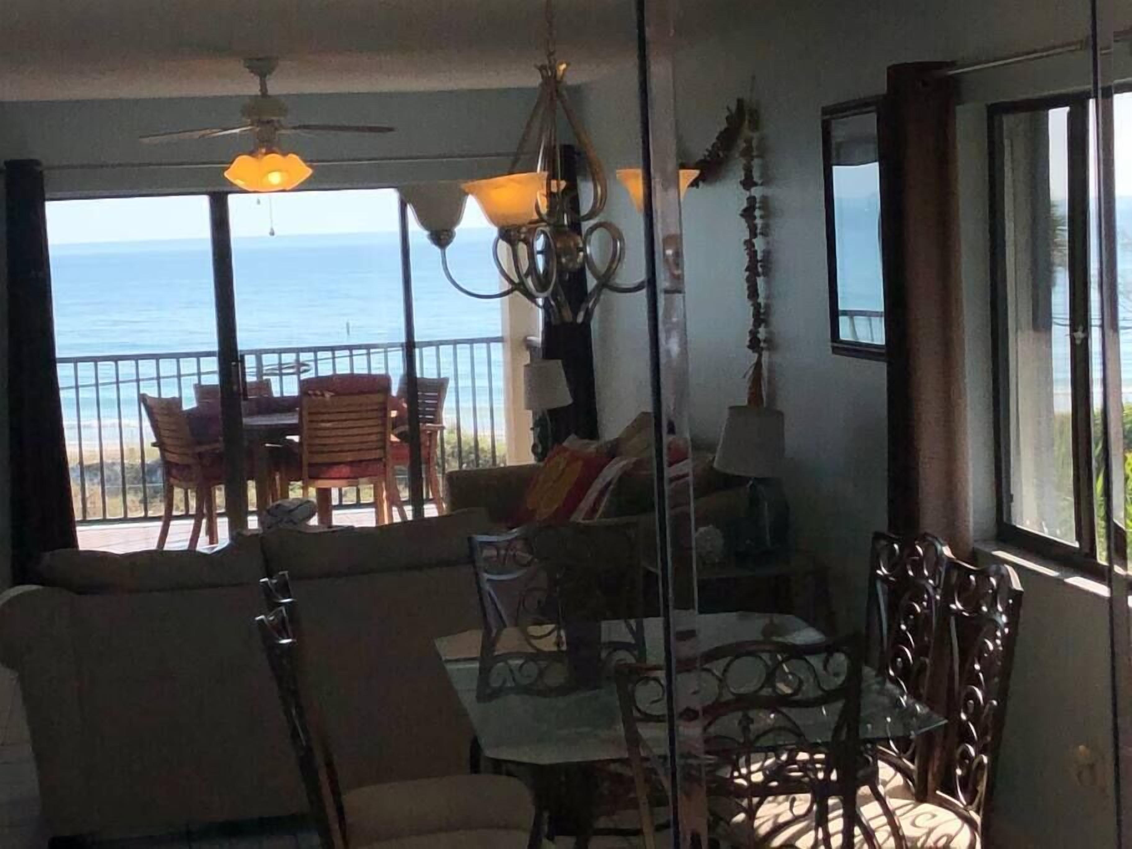 Ein Zimmer mit Balkon und Meerblick, ausgestattet mit einer Couch, Sesseln und einem Esstisch.