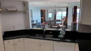 A compact kitchen with white cabinets, a black countertop, and a dishwasher. - AMI Beach + Gulf View Retreat - Dog-friendly (Bradenton Beach)