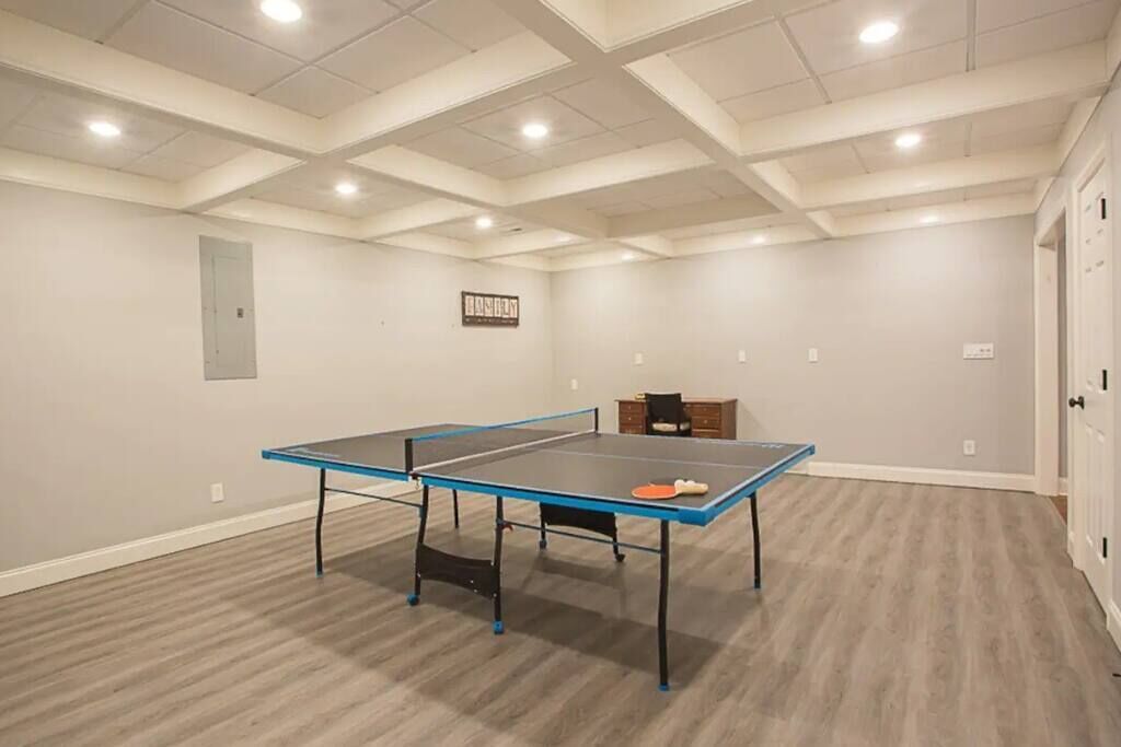 A spacious room with a ping pong table, a small cabinet, and a door.