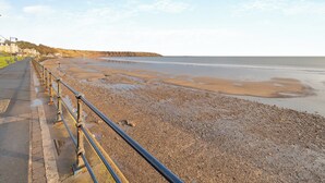 A coastal road with a metal railing, leading to a pebbly beach. - The Landings Apartment 6 (Filey)
