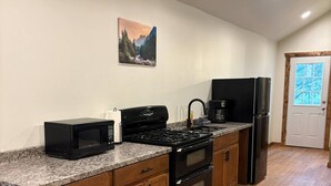 A kitchen with a granite countertop, wooden cabinets, a stove, and a refrigerator. - Piedra River Outpost (Bayfield)