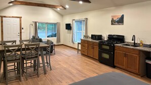 A spacious kitchen with wooden cabinets, a black stove, and a dining area with wooden chairs and a table. - Piedra River Outpost (Bayfield)