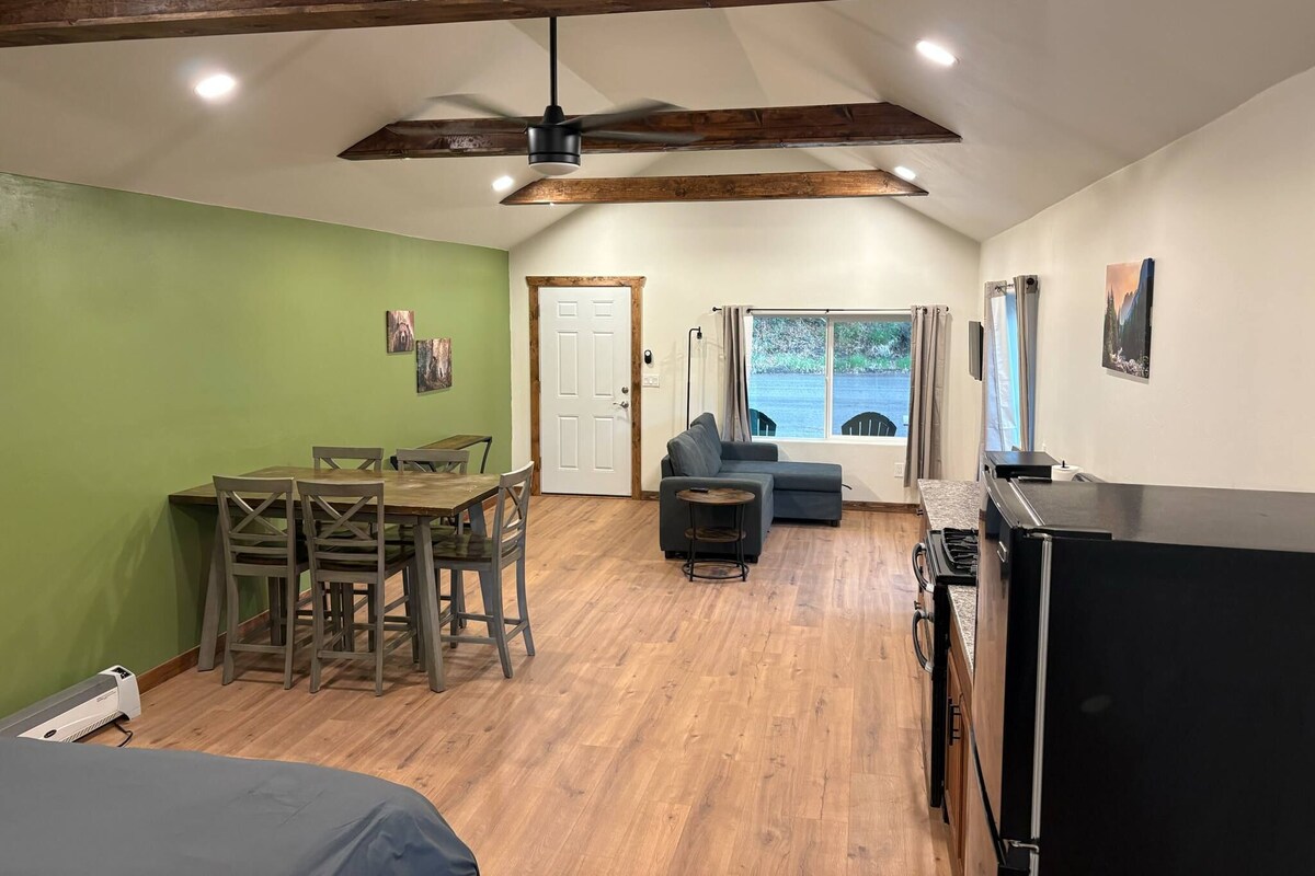 A spacious room with a dining area, a sofa, a TV, and a window with a view.