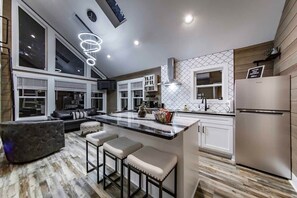 A modern kitchen with a large island, bar stools, and a built-in refrigerator.