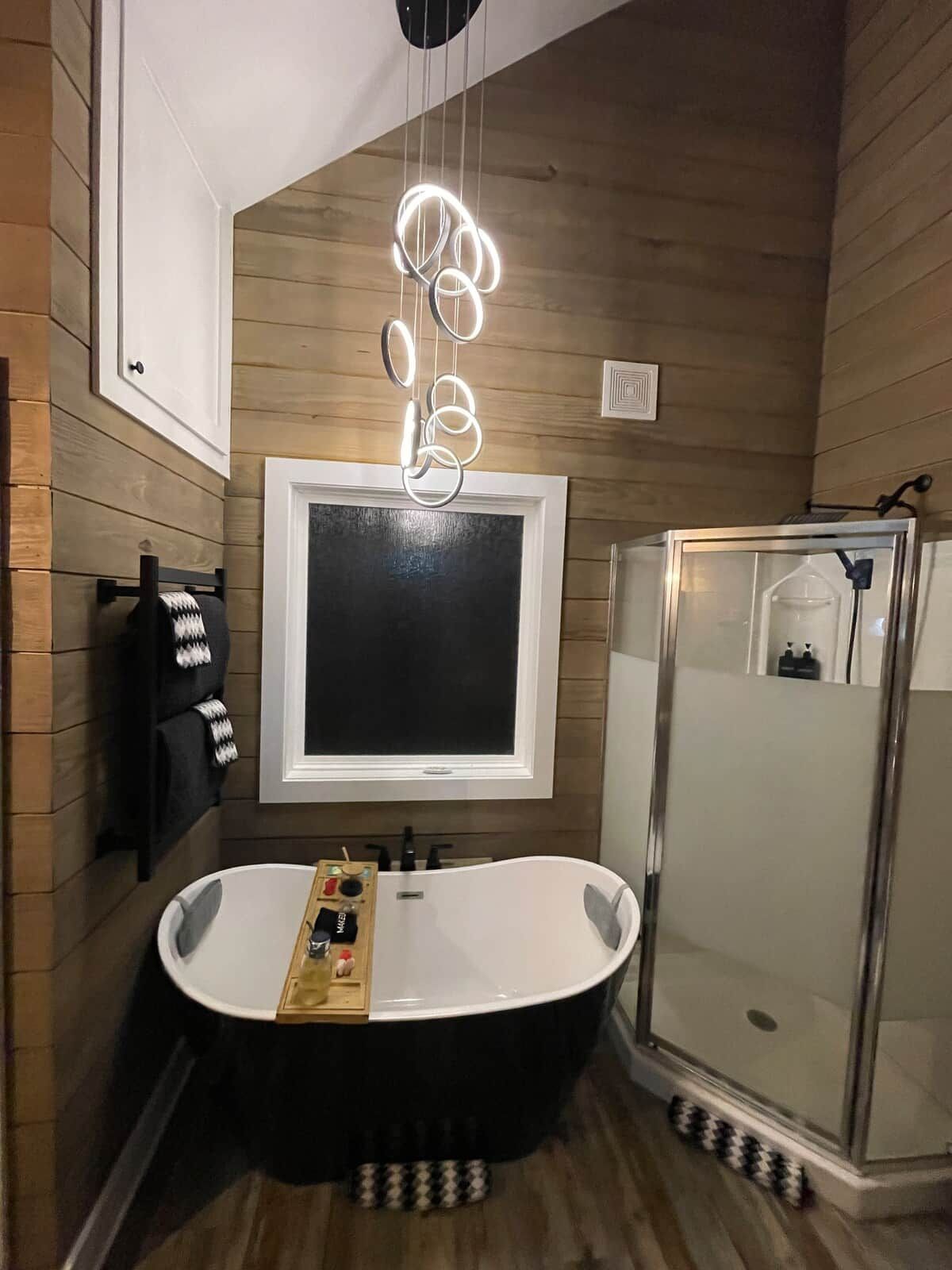 Uma casa de banho moderna com uma banheira independente, um chuveiro com cabine de vidro e um espelho fixado na parede.