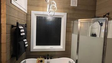 Uma casa de banho moderna com uma banheira independente, um chuveiro com cabine de vidro e um espelho fixado na parede.